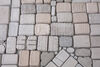 Close up of small cast brick-like objects laid on the floor in a grid.
