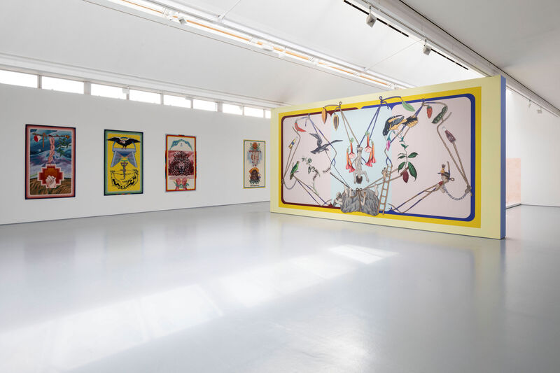 a white gallery space with colourful tuftings on the wall and bright mural in the centre