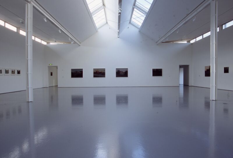 A white gallery covered in canvases with watercolour paintings on them.