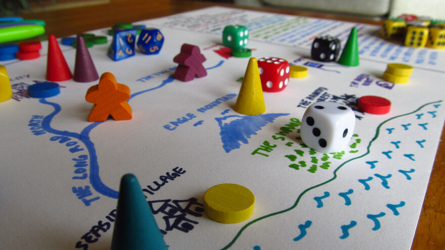 Dice and counters sit on a piece of paper with a map drawn on it.