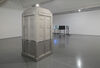 An old fashioned police box stands in the gallery space, painted half white and half grey with a bright white light on top. Beyond this we can see an installation of freestanding monitors facing each other. 