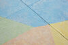 A floor based work is shown in gallery one. The walls are white and the gallery floor is painted grey. On top of this, a sculptural floor is lain in blocks, raising the floor over most of the gallery. This work is brightly coloured, with pastel blue green, yellow orange and pink, in abstract shapes.