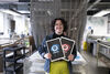Illustrator Katrion Gillon holding two Dundead 2025 screenprints, one red, one blue
