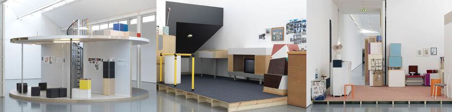 Three photographs of Manfred Pernice's exhibition. Image 1 - From Manfred Pernice's exhibition. A large, circular structure with two floors and a spiral staircase is segmented into different 'rooms' containing boxes and furniture. Image 2 - From Manfred Pernice's exhibition. A palette covered in blue carpet. On top of this, is a collection of furniture - cardboard boxes, a television, and photograph on the wall. Image 3 - A raised platform in Manfred Pernice's exhibition is decorated with mundane objects, including a white chair, a stool, a box with flowers on it, and framed pictures on the wall.