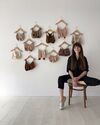 A women sits on a stool in front of many knitted bras 