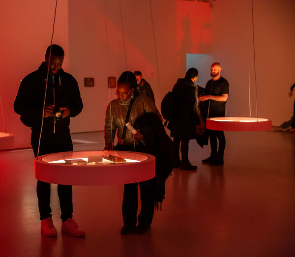 People look at the art in a warmly lit gallery space.