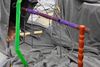 A wire sculpture with coloured plastic around the it sits on crumpled grey fabric