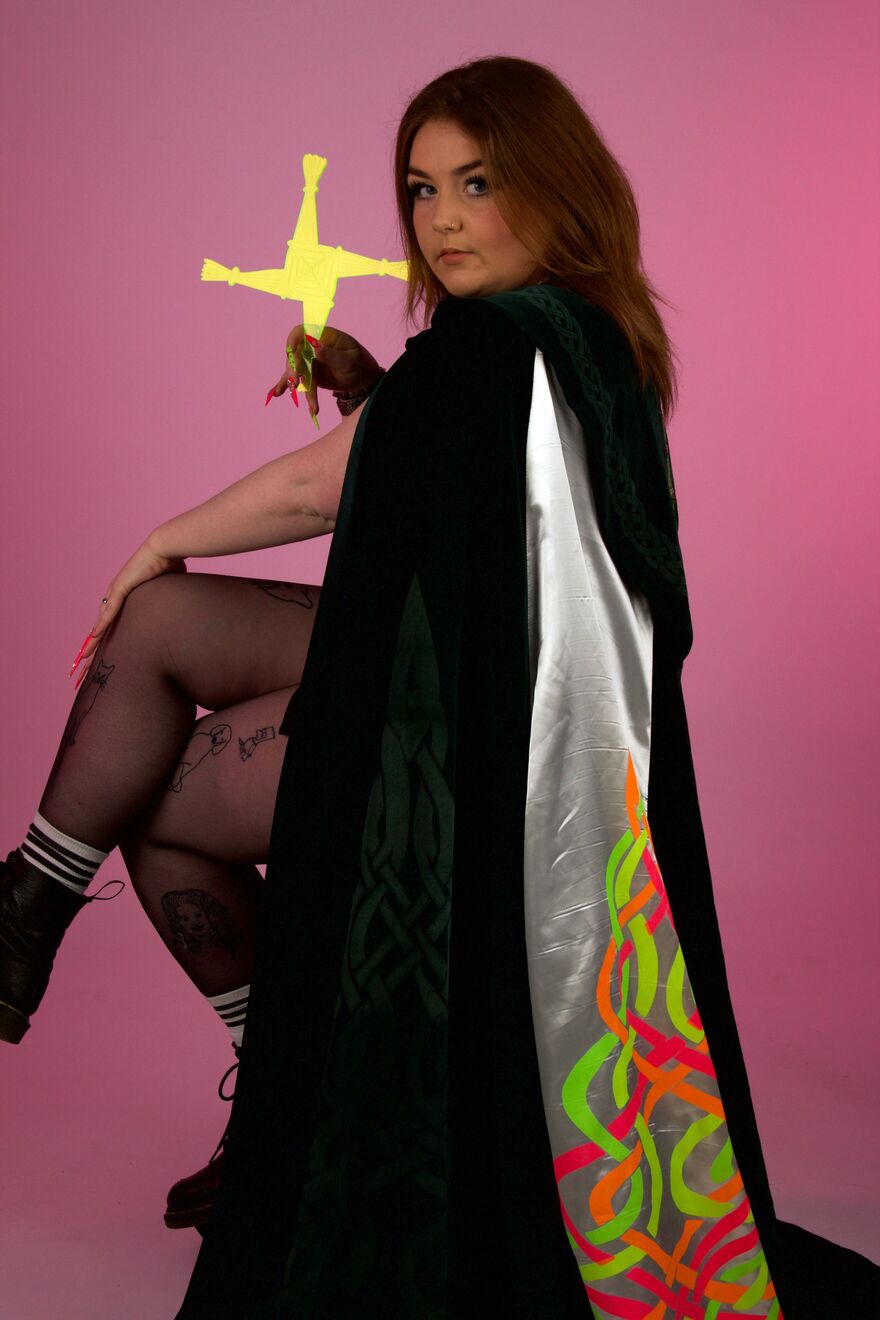 Aoife Cawley sitting on a chair wearing a decorated cape and holding a yellow perspex shape