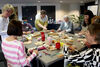 Group of people around a table taking part in a peg loom weaving workshop and chatting