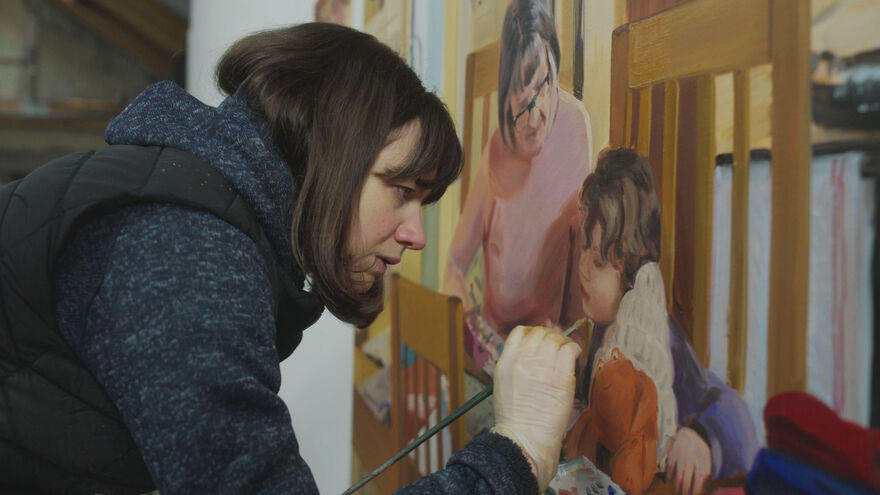 a women leans finishing a painting
