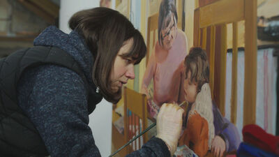 a women leans finishing a painting