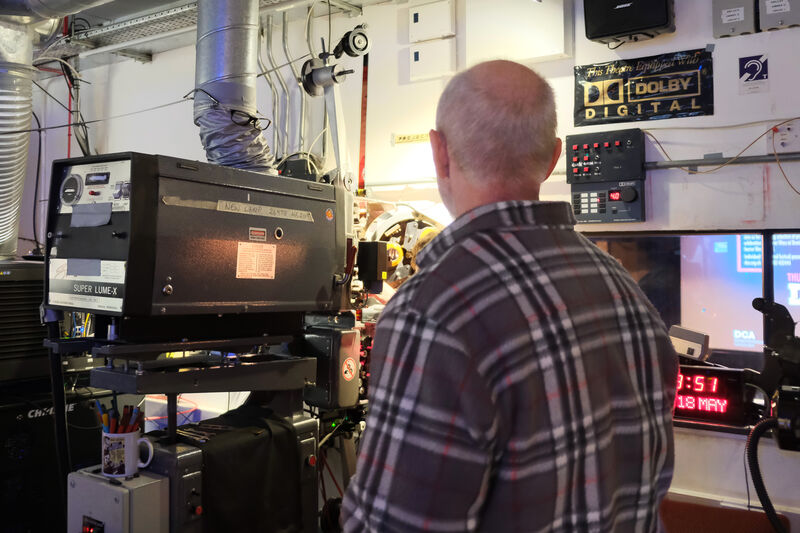 Man in a checked shirt standing in front of a film projector